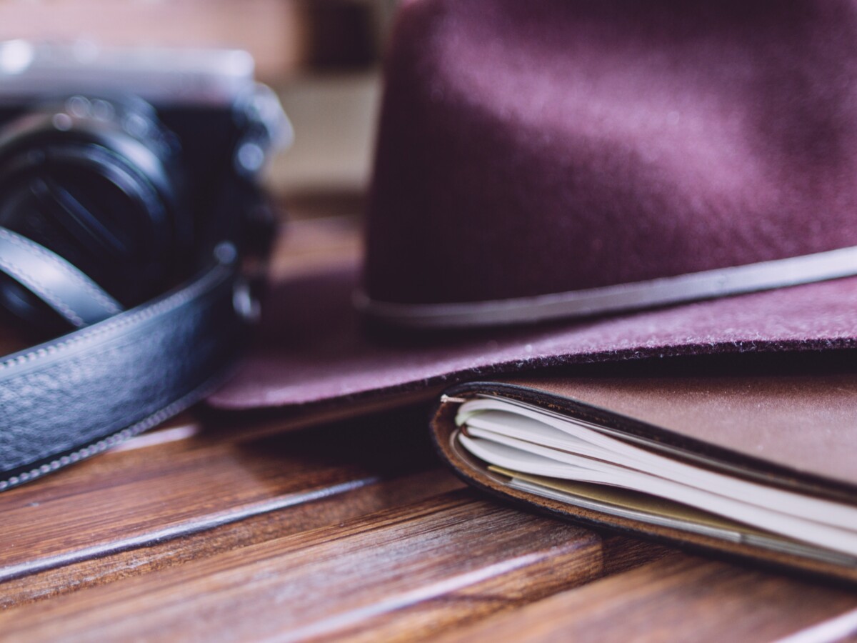 purple hat on books next to leather belt