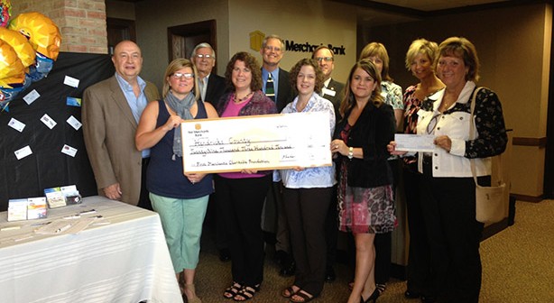 group of people standing behind fundraising check at event